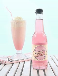 a bottle of pink liquid next to a glass with ice cream