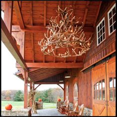 an outdoor dining area with deer antlers hanging from the ceiling and chairs on the floor