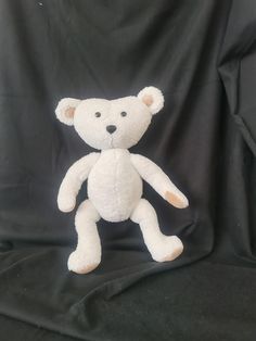 a white teddy bear sitting on top of a black cloth