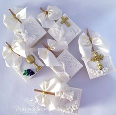 several small white bows with gold crosses on them are laying next to some other items