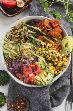 a white bowl filled with salad next to sliced vegetables and avocado on top