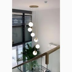 the light fixture is hanging from the ceiling above the stairs in this modern house with white walls and windows