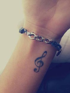 a person with a tattoo on their wrist and a chain around the wrist that has a musical note on it