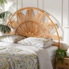 a bamboo headboard with pillows and blankets on it in a white room next to a plant