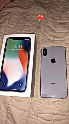 two iphones are sitting next to each other on a bed with the box open