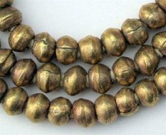 three strands of gold colored beads on a white surface