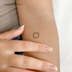 a woman's arm with a small sun tattoo on it