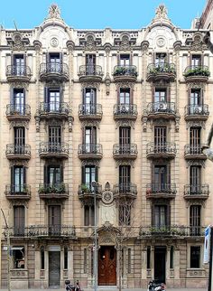 an old building with many balconies on the front and side windows, along with two mopeds parked in front