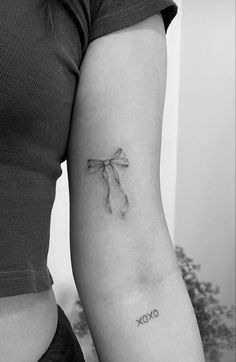 a woman's arm with a tattoo on it that reads oxoxo and has a bow