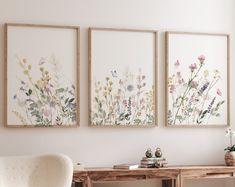 three framed pictures on the wall above a desk with a chair and table in front of it