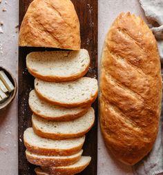 a loaf of bread sliced on top of a cutting board next to slices of bread