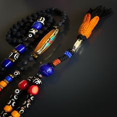 Make a bold statement with the Boho Style Tassel Necklace, a striking and unique piece of handmade jewelry that reflects your wild and free-spirited style. This handcrafted necklace features a combination of black lava rock and Evil Eye Tibetan beads, accented with colorful details and a special handmade tassel. It is not only a fashionable accessory but also a source of positive energy that can be used during yoga and meditation.The black lava rock stones are known for their grounding and calmi Bohemian Lava Stone Jewelry Gift, Handmade Bohemian Lava Stone Jewelry, Bohemian Jewelry With Natural Lava Stones, Spiritual Multicolor Jewelry With Black Beads, Bohemian Black Lava Stone Jewelry, Black Lava Stone Bohemian Jewelry, Bohemian Black Necklaces For Rituals, Artisan Black Necklace With 108 Beads, Black Amulet Jewelry For Festival