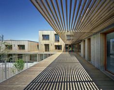 an outdoor walkway with wooden slats leading to two buildings