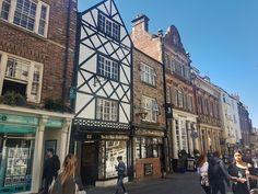 people are walking down the street in front of old buildings