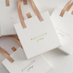 three small white bags with brown handles on top of each other and the words pandasew printed on them