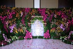 flowers and candles are arranged in front of a floral wall at a wedding reception with the bride's name on it