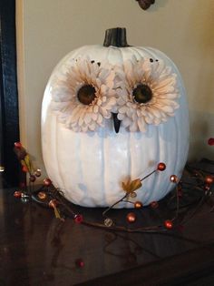 a white pumpkin decorated with flowers and an owl's face