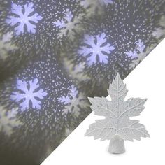 a silver maple leaf brooch sitting on top of a piece of paper with snow flakes in the background