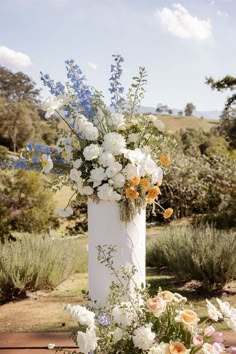 a tall white vase filled with lots of flowers