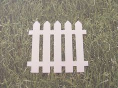 a paper cut out of a white fence in the grass