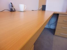 an office desk with a phone and cup on it