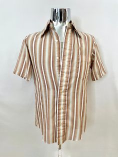 "Vintage 60's H.I.S. Mod, Brown, Striped, Short Sleeve, Shirt (S) This Men's Shirt comes in white polyester/cotton blend with a striped print in brown, yellow, white and blue with short sleeves, front button closure, a single chest pocket and butterfly collar. *The fabric is soft, light weight, without stretch and has a matte surface. Cotton Polyester Made in USA *This Shirt is in excellent condition with a faint mark on the bottom left side (photo #10) *Free shipping within the US. Size: (S) Chest: 40\" Sleeve Length: 10\" (outside) and 6\" (inside) Length: 28 1/2\" (front) 30\" (back)  Shoulder to Shoulder: 16\" Weight: 5 oz *Follow FreshandSwanky on Instagram" Classic Brown Short Sleeve Shirt For Summer, Classic Brown Camp Shirt For Summer, Retro White Collared Shirt, Retro Fitted Camp Shirt For Spring, Retro Fitted Short Sleeve Shirt, Fitted Brown 1970s Style Tops, Fitted Brown Tops In 1970s Style, White Fitted Camp Shirt For Spring, Fitted Brown Tops 1970s Style