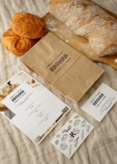 bread and pastries sitting on top of a bed next to each other in front of a paper bag