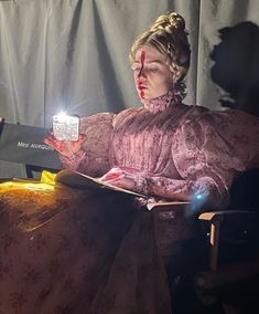 a woman sitting in a chair reading a book with a light shining on her face