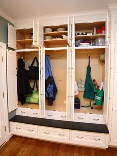 an organized mudroom with white cabinets and wood floors