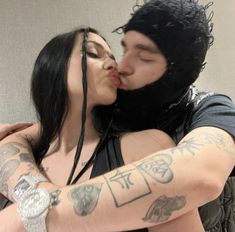 a man and woman kissing each other with tattoos on their arms