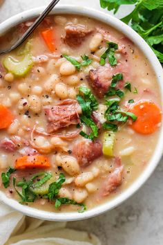 a white bowl filled with ham and bean soup, garnished with parsley