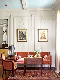 a living room filled with furniture and paintings on the wall above it's windows