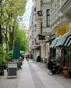 the sidewalk is lined with tables and umbrellas