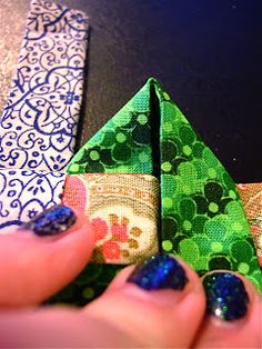 a woman's hand holding an origami piece with blue and green designs on it