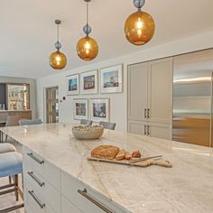 a kitchen with marble counter tops and gold pendant lights hanging from the ceiling above it