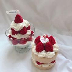 two small cakes with strawberries on top are sitting next to each other in glass bowls