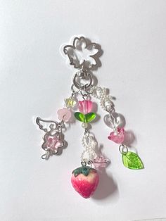 a close up of a key chain with an apple and other charms on it's side