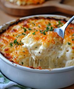 a spoonful of cheesy potato casserole being lifted from a dish