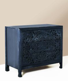 an ornate black wooden cabinet with carvings on the front and sides, against a beige background