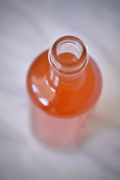 an orange liquid bottle sitting on top of a white surface