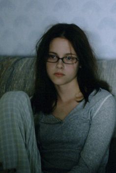 a woman sitting on top of a couch wearing glasses