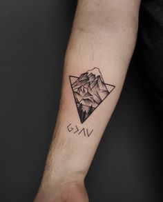 a man's arm with a mountain and triangle tattoo on the left inner forearm