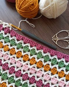 a crocheted blanket with yarn and scissors on the table