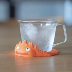 an orange toy is sitting in front of a cup with foam on it and water inside