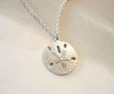 "Sand Dollar Necklace Silver Sand Dollar Pendant Beach Jewelry Bridesmaid Necklace Sand dollar Necklace Ever stroll the beach and come upon a sand dollar, well it would be you're lucky day, they are real living creatures and are so beautiful. Sand dollar measures approx. 24 mm x 23mm or 1\" in diameter. A silver matte silver dollars hangs from silver chain. The silver dollar is so realistic looking, it is a matte silver and is slightly domed like a real sand dollar. You can feel the detail in th Ocean-inspired Jewelry With Lobster Clasp For Vacation, Ocean-inspired Jewelry For Vacation With Lobster Clasp, Coastal Jewelry For Beach Season Vacation, Coastal Jewelry For Beach Vacation, Coastal Beach Season Jewelry For Vacation, Coastal Style Jewelry For Beach Vacation, Coastal Style Beach Vacation Jewelry, Ocean-inspired Sterling Silver Beach Jewelry, Sand-colored Strand Jewelry For Vacation