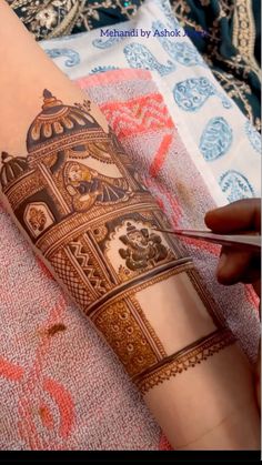 a woman is getting her hand painted with hendi on the side of her arm