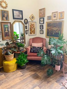 a living room filled with lots of potted plants and pictures on the wall above