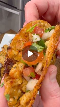 a person holding a piece of bread with toppings on it and an appetizer in the background