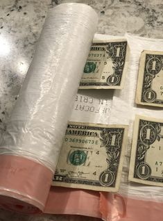 three rolls of toilet paper wrapped in plastic and one roll of money on the ground