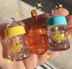 three baby bottles with yellow rubber ducks in them, one is blue and the other is orange